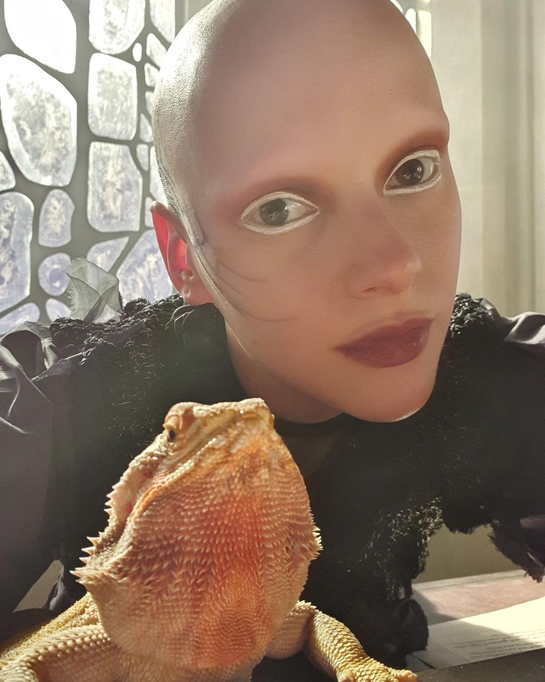 A behind the scenes picture of actress and singer Joelle playing the character Joelle with her bearded dragon on the set of the Netflix movie The School for Good and Evil.